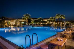 a pool at night with tables and chairs at Avithos Resort Hotel in Svoronata