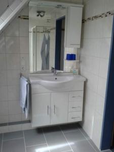 a white bathroom with a sink and a mirror at Ferienwohnung Möwe, Perle im Dreieck Bensersiel, Neuharlingersiel, Esens in Neuharlingersiel +10 photos