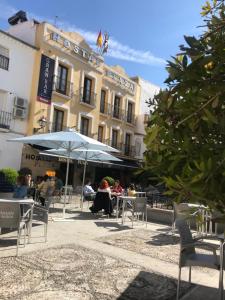 a group of people sitting at tables in front of a building at Hostal Plaza in Marmolejo