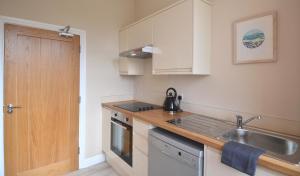 a kitchen with white cabinets and a sink at Towennan - four bedroomed apartment in quiet seaside village. in Gwithian