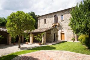 une grande maison en pierre avec une cour herbeuse dans l'établissement Villa Teloni, à San Severino Marche