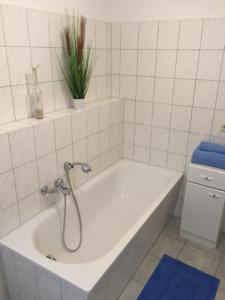 - une salle de bains blanche pourvue d'une baignoire avec une plante dans l'établissement Altstadt-Ferienwohnung, à Tangermünde