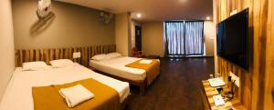 a hotel room with two beds and a flat screen tv at Sharada Residency in Somvārpet