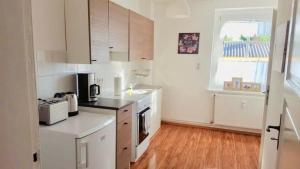 a kitchen with white appliances and a wooden floor at Ferienwohnungen in der Uckermark in Schönermark