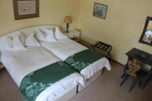 a bedroom with a white bed with green and white pillows at Hansa Hotel Swakopmund in Swakopmund