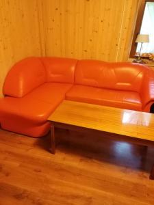 an orange leather couch with a wooden coffee table at Świerkowe Zacisze Domki in Budzów