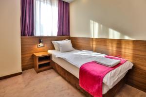 a bedroom with a bed with a pink blanket on it at Boutique Hotel Golden Star in Tuzla