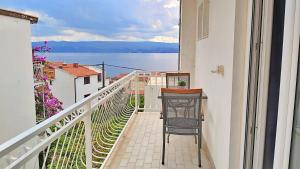 a balcony with a chair and a view of the water at Apartments Nemira in Omiš