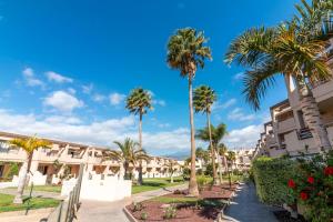 a row of palm trees in front of a building at HomeForGuest Spacious and bright flat on the beach La Tejita in Granadilla de Abona