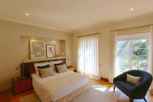 een slaapkamer met een bed, een stoel en een raam bij Villa Casa da Luz, Palmyra 173 - Clever Details in Vilamoura +49 foto's