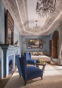 una camera blu con un letto e un lampadario a braccio di La Sultana Marrakech a Marrakech