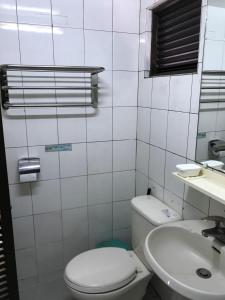 bagno bianco con servizi igienici e lavandino di Guang Haw Hotel a Tainan