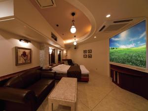 a room with a couch and a bed and a large window at Hotel Fine Garden Sakai in Sakai