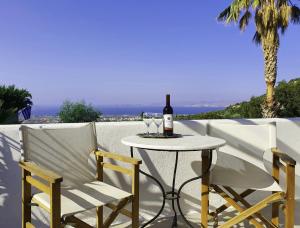 a table with a bottle of wine and two chairs at Orea Ellas Kos - Deluxe Residences in Lagoúdi Zía