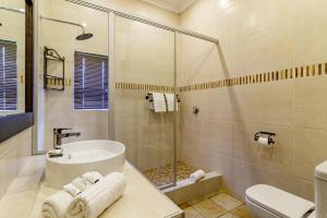 a bathroom with a sink and a shower and a toilet at Nkomazi Kruger Lodge & Spa in Malelane