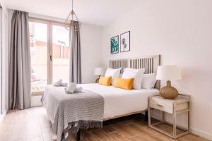 biała sypialnia z dużym łóżkiem z pomarańczowymi poduszkami w obiekcie Feelathome Goya Apartments w Madrycie