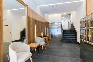 hol z białymi krzesłami, stołem i schodami w obiekcie Feelathome Goya Apartments w Madrycie