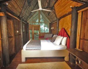 Un dormitorio con una cama en una cabaña de madera. en Tortugal Boutique River Lodge, en Río Dulce