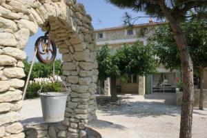 un mur en pierre avec un seau devant un bâtiment dans l'établissement Locations des Alpilles, à Saint-Rémy-de-Provence