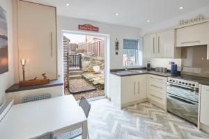a kitchen with white cabinets and a view of a yard at Host & Stay - The Cottage, Marske in Marske-by-the-Sea