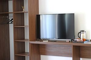 TV de pantalla plana en la parte superior de una estantería de madera en Pensiunea Casa Iorgovanul Urseni, en Timisoara