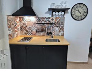 een keuken met een wastafel en een klok aan de muur bij Complejo Apartamentos Rurales Molino de Abajo in Ribera Baja