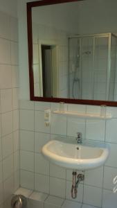 ein weißes Badezimmer mit einem Waschbecken und einem Spiegel in der Unterkunft Boardinghouse Vegesack in Bremen-Vegesack