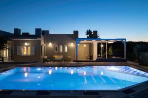 a swimming pool in front of a house at night at Villa Periklis in Adelianos Kampos