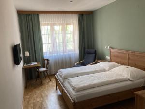 ein Schlafzimmer mit einem Bett, einem Stuhl und einem Fenster in der Unterkunft Zöchbauer Gästehaus - Hotel Garni in Kapelln