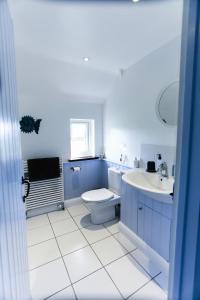 a blue bathroom with a toilet and a sink at Linden House in West Wittering