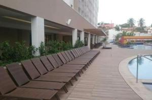 eine Reihe von Bänken neben einem Gebäude mit Pool in der Unterkunft Enjoy - Olimpia Park Resort - Em frente ao Park - Ap 1 Dorm in Olímpia