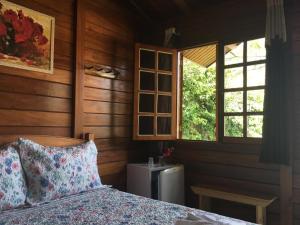ein Schlafzimmer mit einem Bett, zwei Fenstern und einem Heizkörper in der Unterkunft Chalés Eucaliptos in Monte Verde