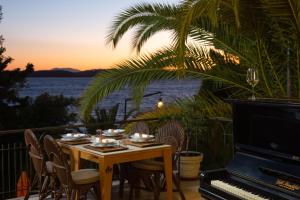 a table with chairs and a piano on a balcony with the ocean at Hotel Podstine in Hvar