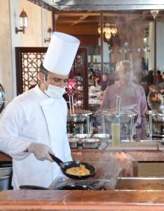 a chef in a kitchen preparing food in a wok at Pearl Continental Hotel Malam Jabba in Swat