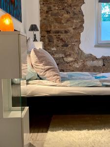 a bed in a room with a brick wall at Eifelstein, Apartment mit Whirlpool und Ofen in Dahlem