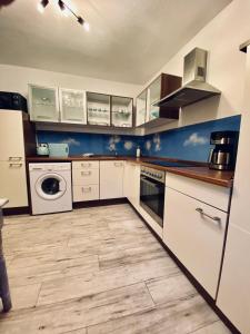 a kitchen with white cabinets and a washer and dryer at Eifelstein, Apartment mit Whirlpool und Ofen in Dahlem