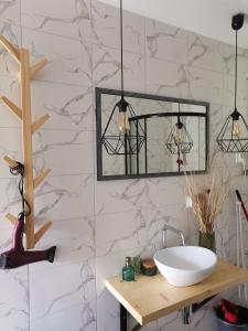 a bathroom with a sink and a mirror at Bieszczadzkie BOHO stodoły z jacuzzi i sauna na wyłączność in Myczkowce