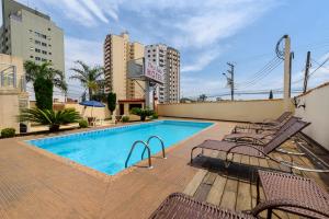 a swimming pool with chairs next to a building at Plaza Suite Hotel in Taubaté