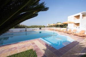 a swimming pool with chairs and a building at Elena Rooms & Apartments in Gerani Chanion
