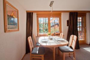 a dining room with a table and chairs and windows at Haus Lizi, Apartment 8 in Zermatt