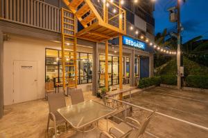 チェンマイにあるBEDGASM Hotel x Cafe Nimmanの建物の前にパティオ(テーブル、椅子付)