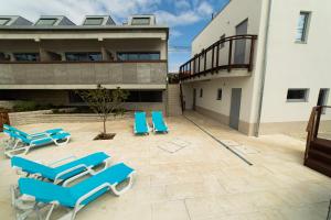 a patio with blue lounge chairs and a building at Albergaria da Tomásia in Aldeia do Meco