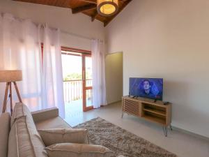 uma sala de estar com um sofá e uma televisão de ecrã plano em Cerrado Ville em Alto Paraíso de Goiás