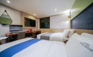 Habitación de hotel con 2 camas y escritorio con ordenador en The Stone Bridge Hotel Dongnae en Busan