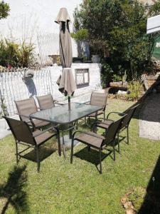 ein Tisch mit Stühlen und ein Regenschirm auf dem Rasen in der Unterkunft 36 Mount Road Guesthouse and Self Catering in Port Elizabeth