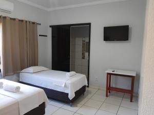 a hotel room with two beds and a television at Pousada Braga in Palmas