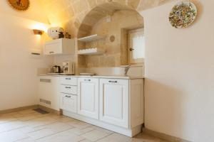 cocina con armarios blancos y suelo de baldosa en La Corte Dei Pastori en Matera