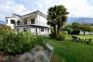 una gran casa blanca con una palmera y bancos en La Magnolia, en Ornavasso
