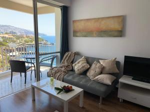 un soggiorno con divano e vista sull'oceano di Apartamento do Mar e Lua a Funchal