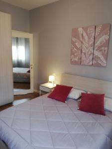 1 dormitorio con 1 cama blanca grande con almohadas rojas en Franciacorta flat & bollicine en Passirano